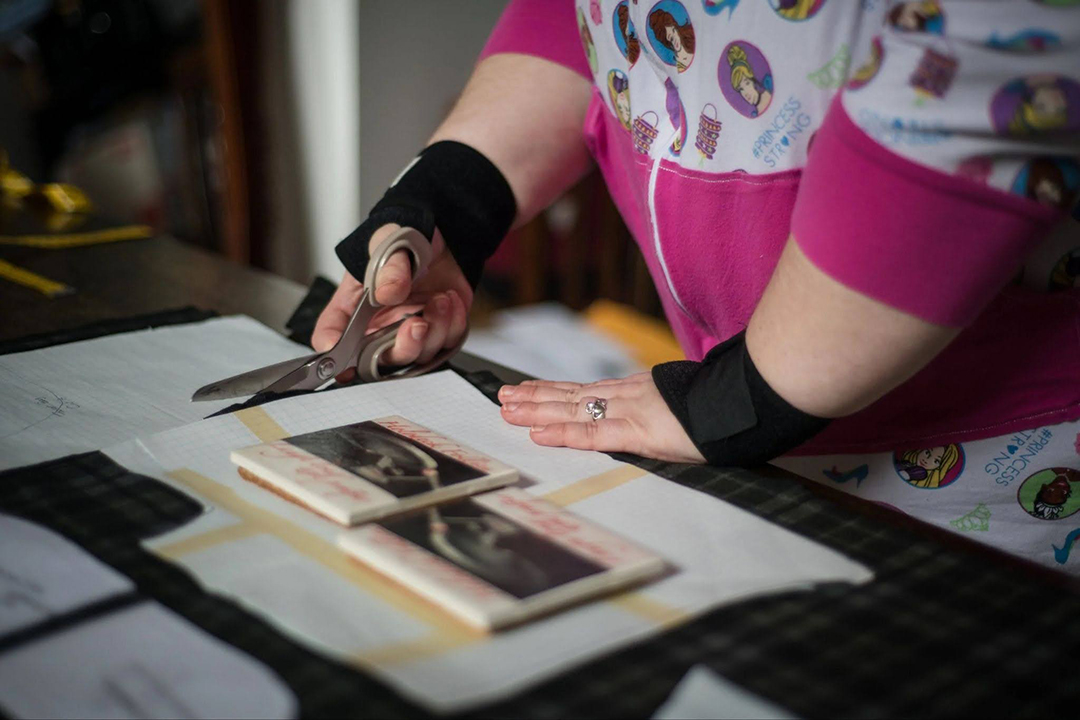 Close up of artist cutting material with scissors.